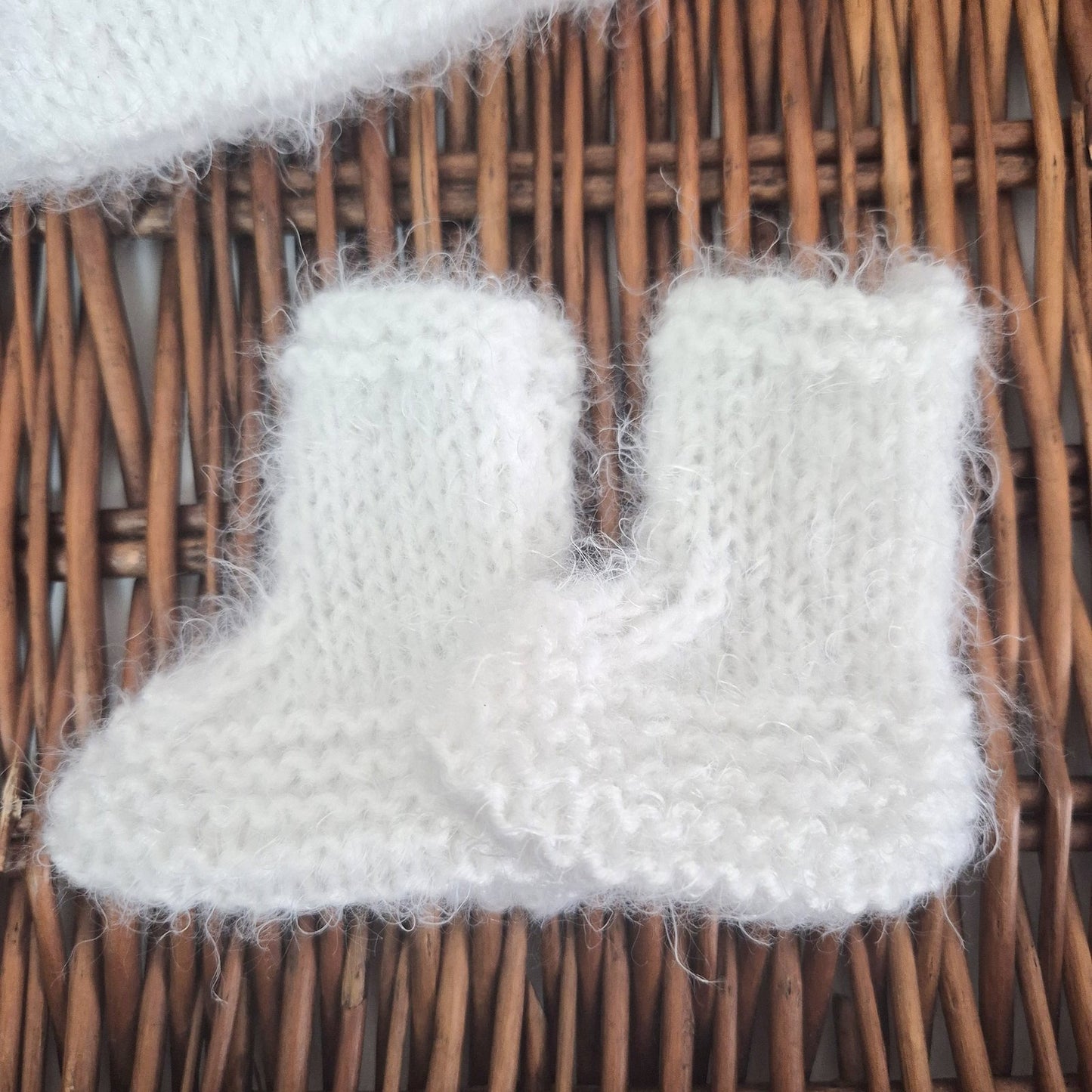 White knitted booties on a wicker surface