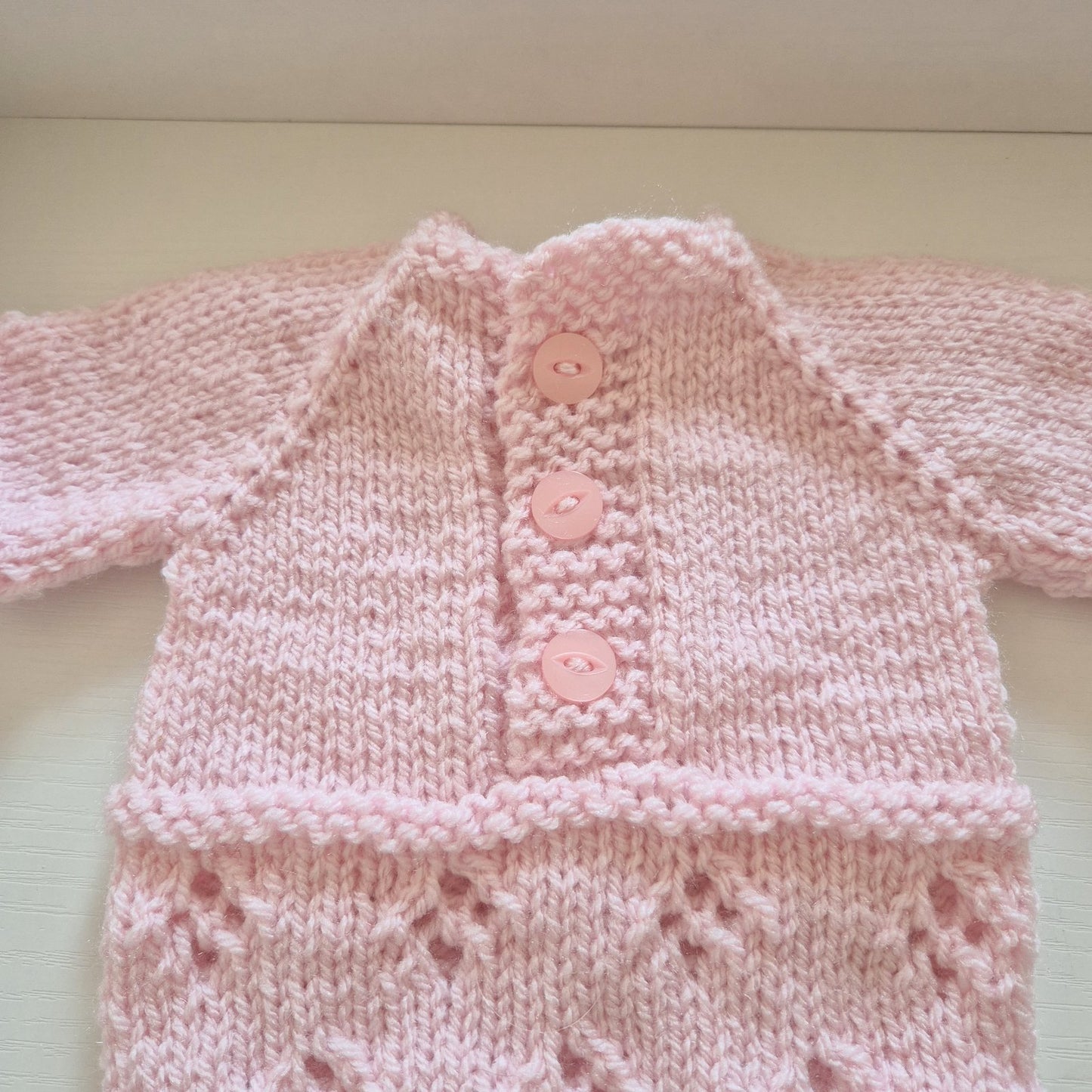 Pink Handknit Newborn Baby Romper and Bonnet Set. Knit in soft quality acrylic yarn, in an eyelet lace pattern. This short sleeved bodysuit style romper is suitable as a hospital coming home outfit, newborn photo prop or baby shower gift. Ready to send.
The little romper has buttons at the neck that can be worn to the back or the front, and for buttons for quick diaper changes.
Shipped from the UK, in an organza bag that is ready for you to gift.