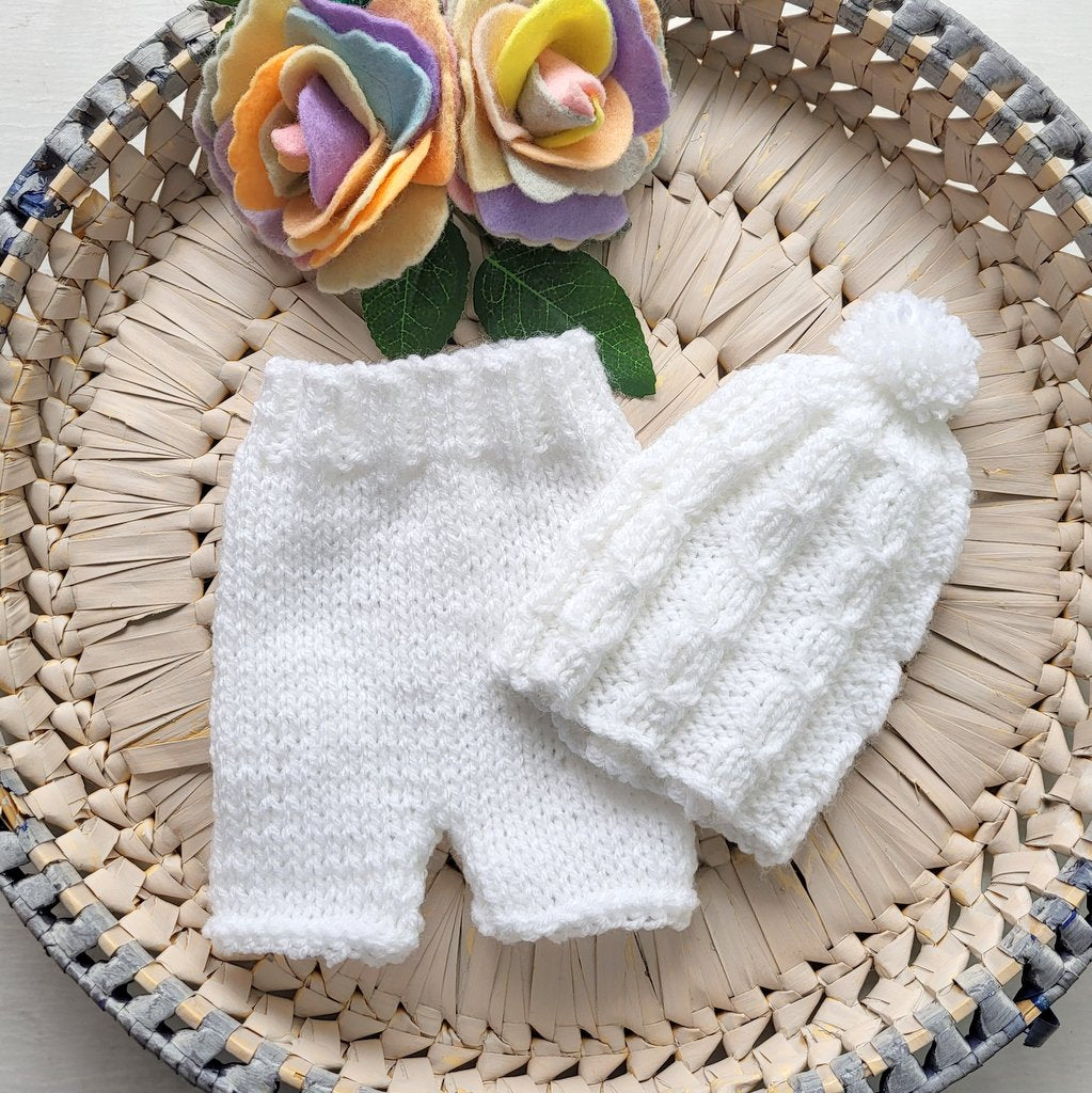 white knitted newborn baby shorts and cabled pom pom hat set