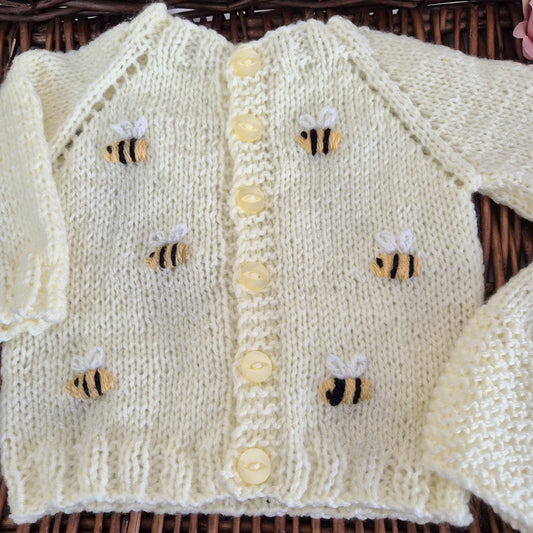 Knitted baby cardigan with bee patterns on a woven surface