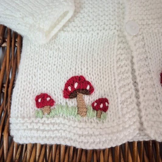 White hand knit baby cardigan with embroidered red toadstools. Jumper, 0-3 months Sweater
A gorgeous hand knit baby cardigan to fit a baby of 0-3 months This little jumper has white buttons on the top of the bodice, with little red toadstools embroidered on the front. 