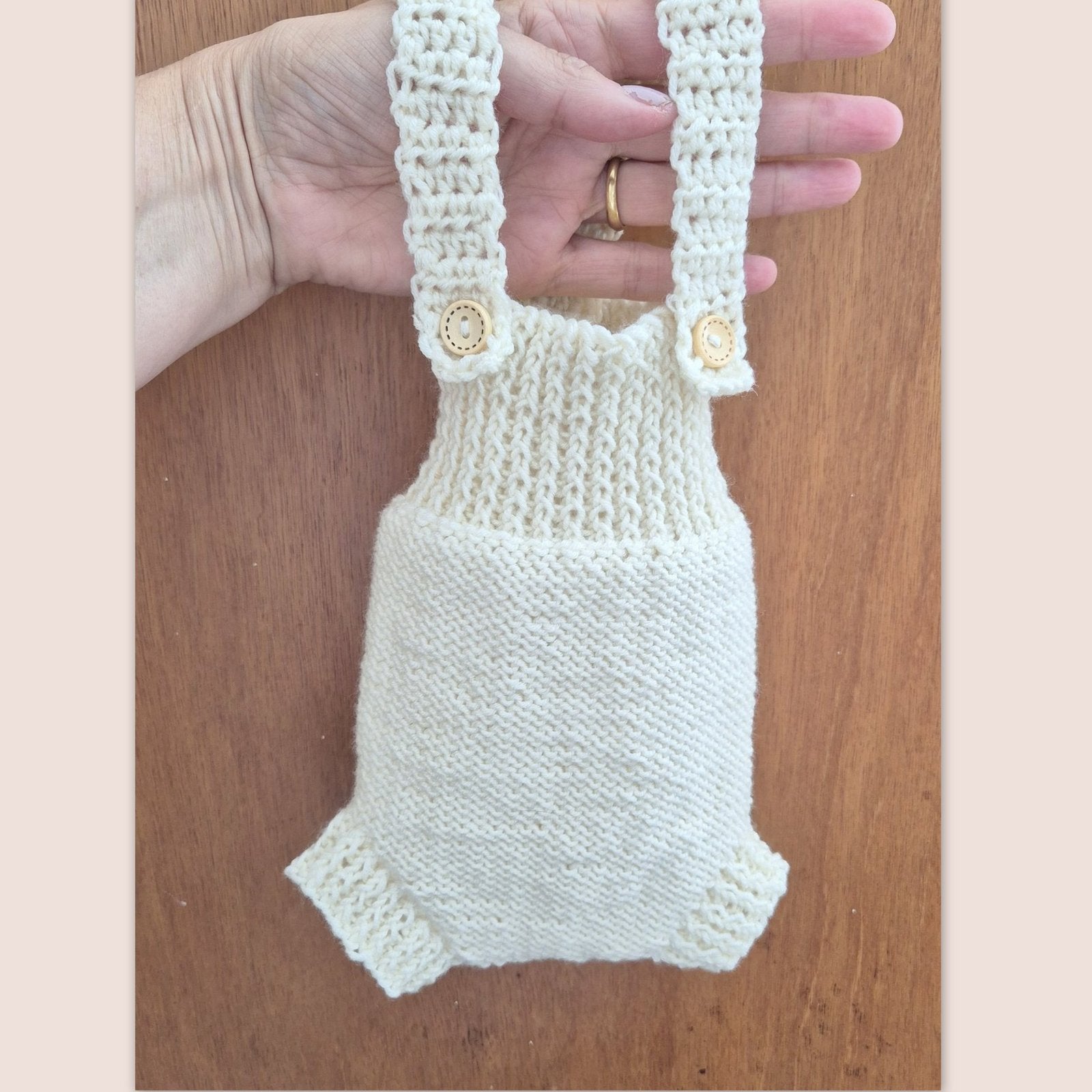 Ready to send knitted baby romper with shoulder straps, suitable for newborn photography.
Knit in cream merino yarn, this little dungaree type romper has a wide ribbed chest, and garter stitching on the tummy/ diaper.