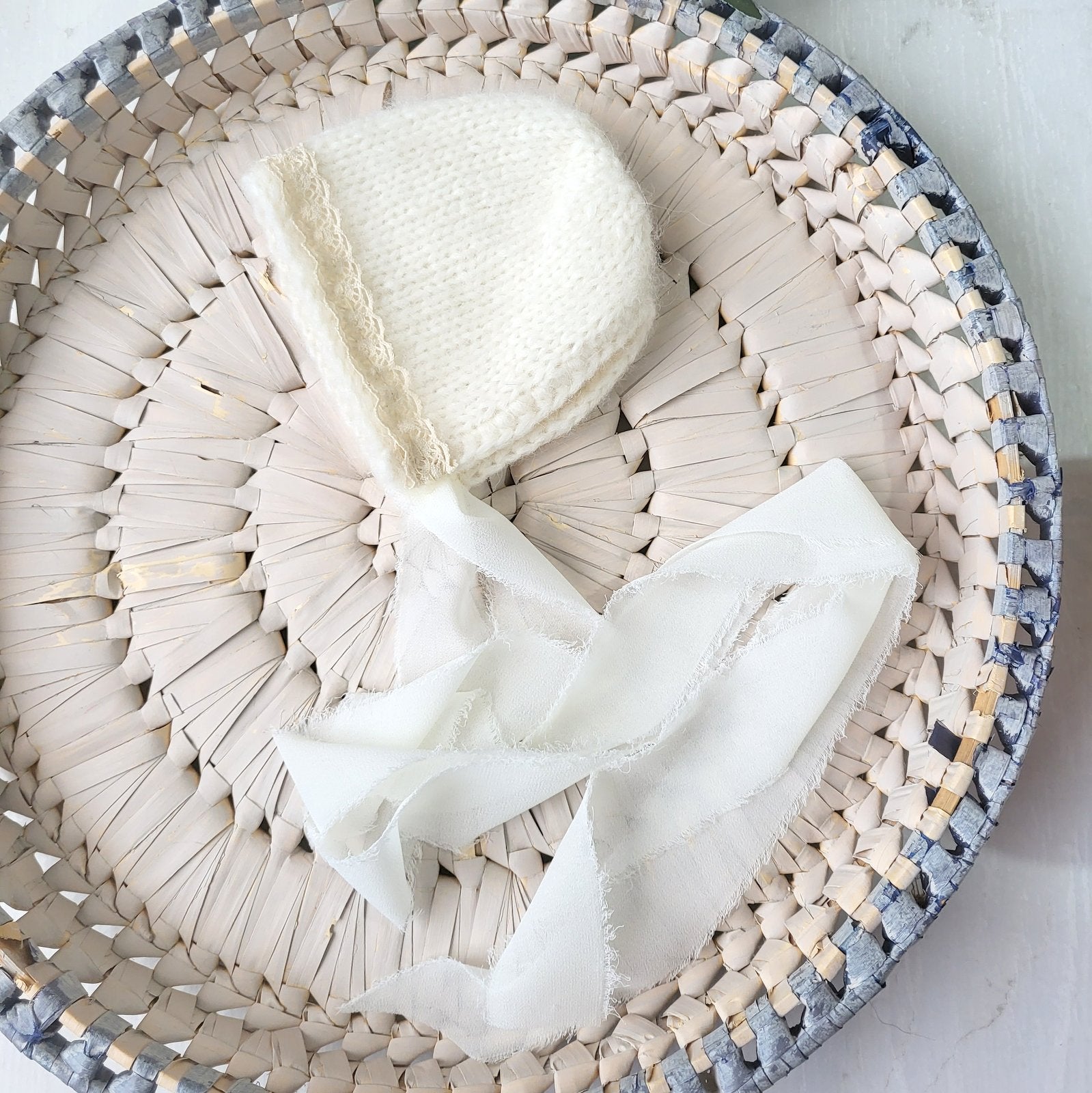 cream knitted baby bonnet with frayed ribbons and vintage lace trim