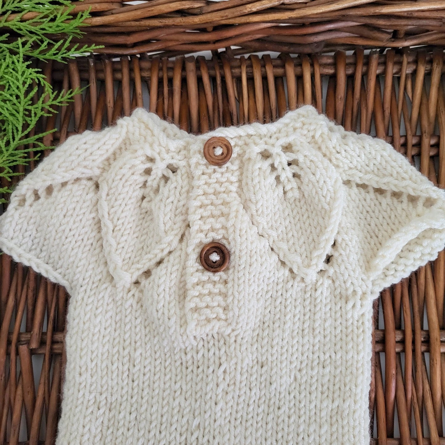 closeup of a knitted baby romper with leaft pattern