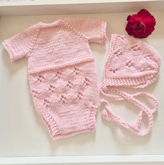 Pink Handknit Newborn Baby Romper and Bonnet Set. Knit in soft quality acrylic yarn, in an eyelet lace pattern. This short sleeved bodysuit style romper is suitable as a hospital coming home outfit, newborn photo prop or baby shower gift. Ready to send.
The little romper has buttons at the neck that can be worn to the back or the front,&nbsp; and for buttons for quick diaper changes.
Shipped from the UK, in an organza bag that is ready for you to gift.