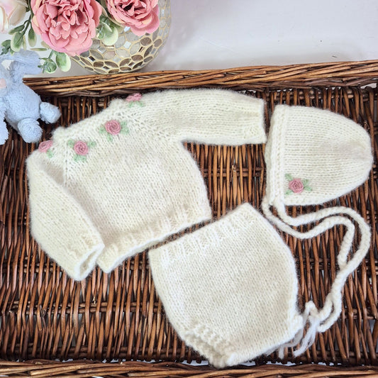 Cream Knitted Baby Girl Coming Home Outfit with pink embroidered roses. Newborn Photo Prop.
This adorable set includes a hand made sweater, pants and bonnet. All knit in soft cream alpaca yarn, with flowers embroidered around the neckline.