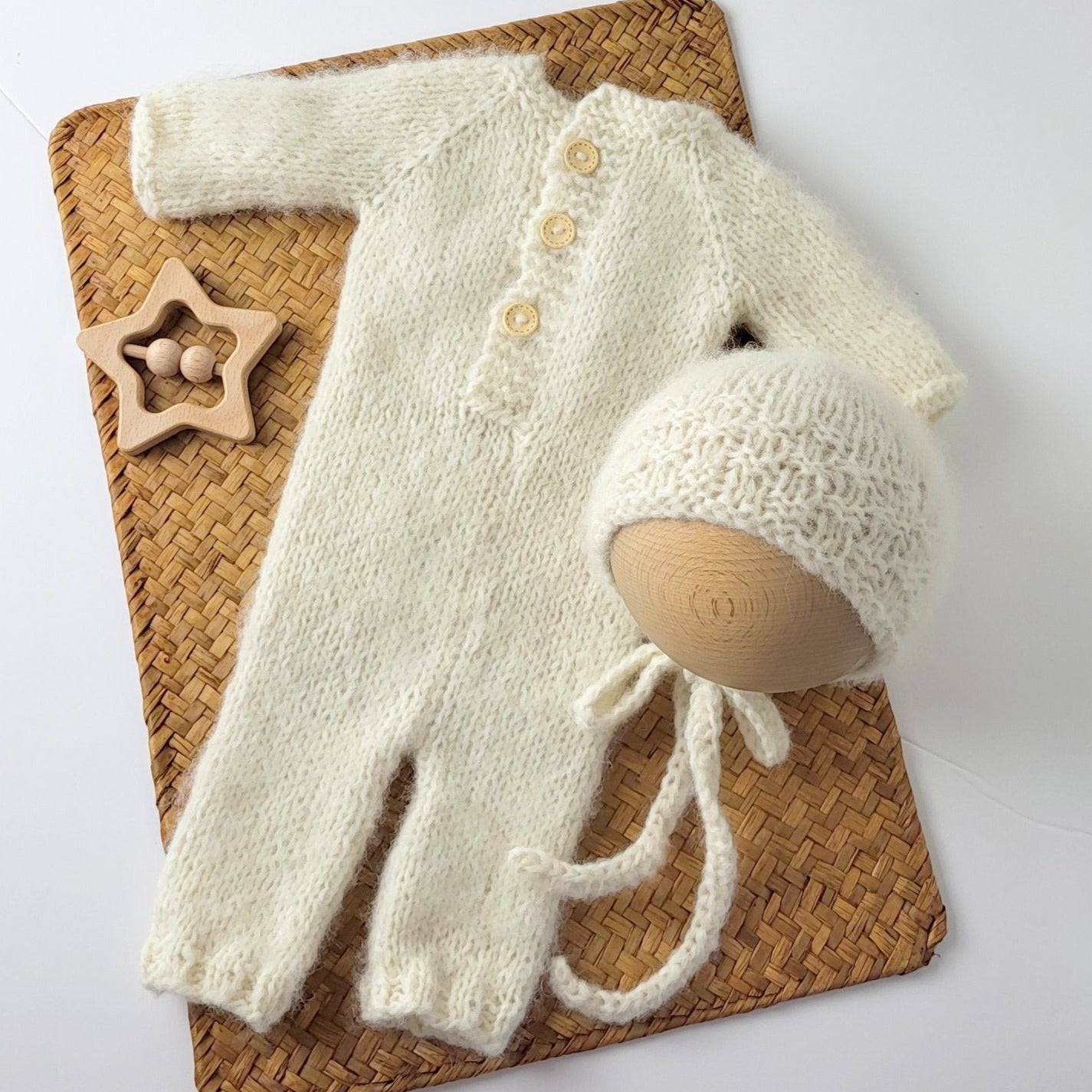 cream knitted newborn rompe with long sleeves, buttons down the front, and classic style bonnet