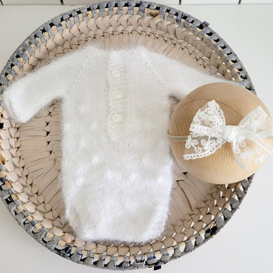 white knitted long sleeved romper in a fluffy yarn, for newborn baby photo prop use. the romper comes with a free bow headband for baby girls