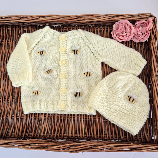 A Yellow hand knit baby cardigan and hat set for a baby 0-6 months old, embroidered with bumble bees. The&nbsp; round necked cardigan buttons down the front , and is embroidered with little yellow and black bumble bees. A matching hat with bee motif completes the set.

Suitable for a baby boy or girl, perfect as a baby shower gift.
The set is shipped in a white voille bag with a ribbon tie, so that you can easily gift it.

The outfit is designed to fit a baby of approximately 0-6 months. The chest measures 