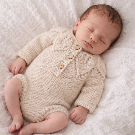 beige knitted newborn romper with long sleeves and a leaf pattern on the top.