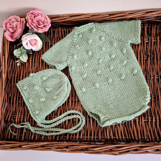 Handmade knitted sage green newborn baby romper and bonnet set. Ready to send.

The bodysuit-style romper outfit has all-over popcorn bubble texture, with short sleeves. It has wooden button fastenings at the back neck and diaper opening, designed for newborns under 20 days old. Perfect as a hospital coming home outfit, newborn photography prop, or baby shower gift.

Knitted using my own original designs, shipped ready to gift&nbsp; in an organza bag. Dispatched from the UK.

Ideal for first photos and spec