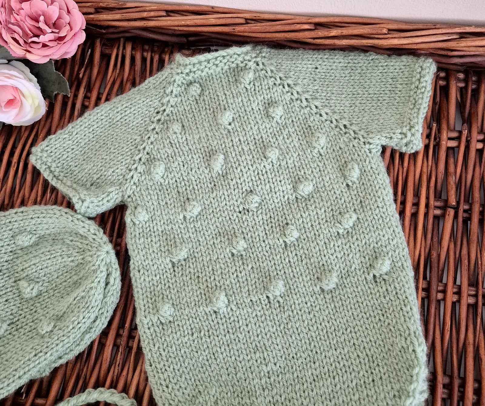 Knitted baby outfit with a hat on a wicker surface