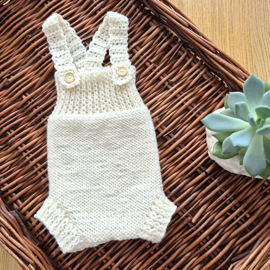 Ready to send knitted baby romper with shoulder straps, suitable for newborn photography.
Knit in cream merino yarn, this little dungaree type romper has a wide ribbed chest, and garter stitching on the tummy/ diaper.