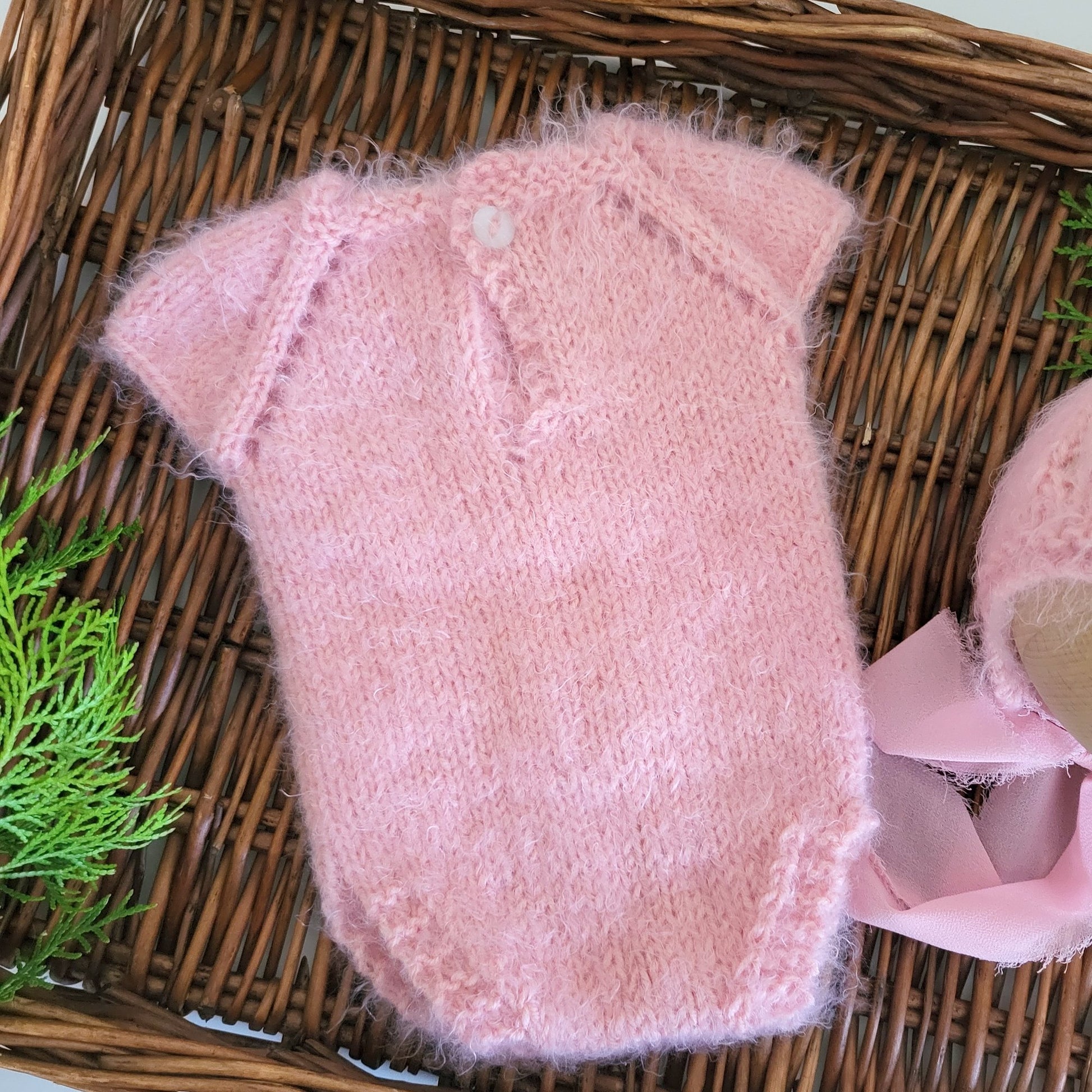 soft and fuzzy pink newborn baby girl romper with a bonnet with ribbon ties