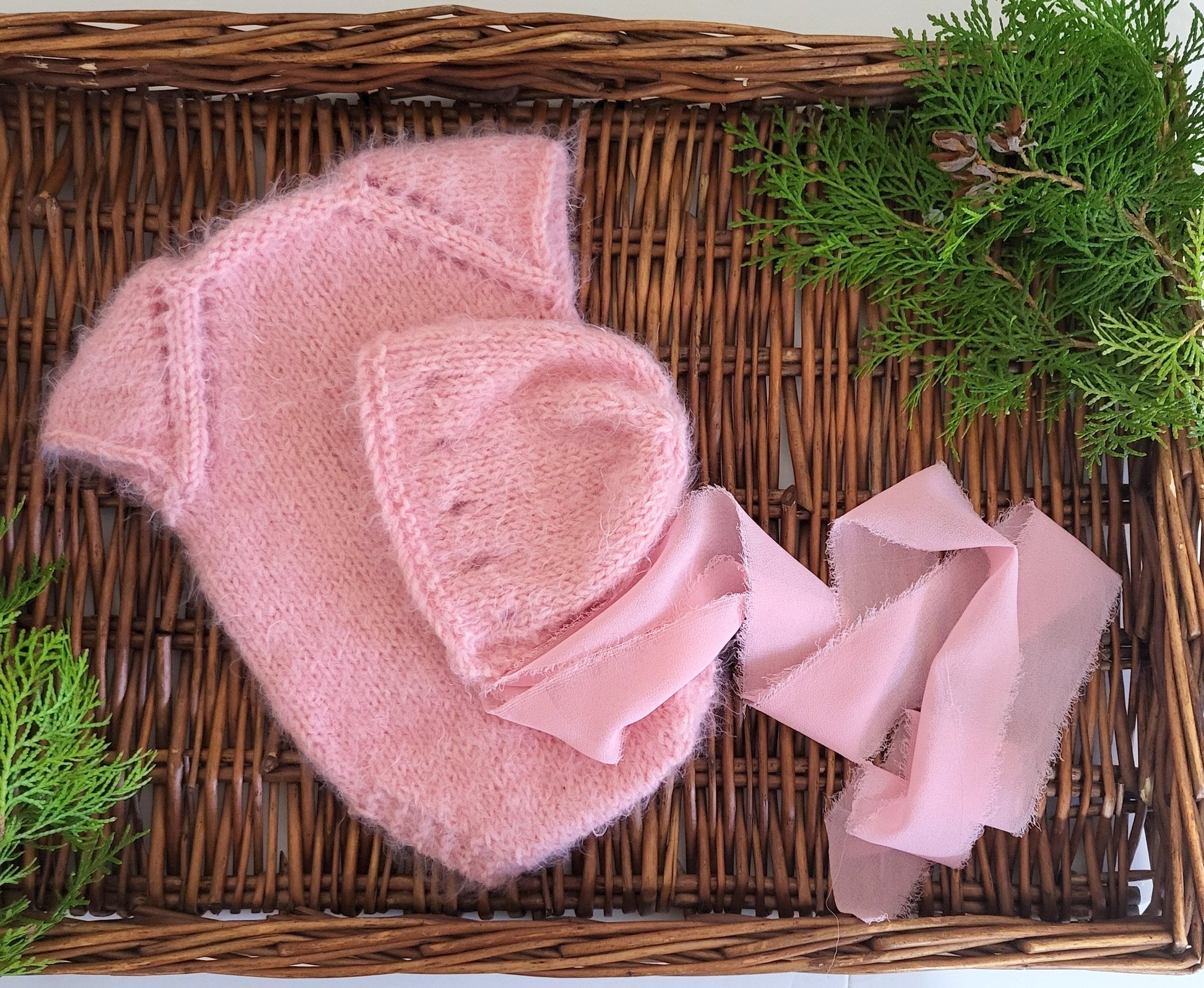 soft and fuzzy pink newborn baby girl romper with a bonnet with ribbon ties