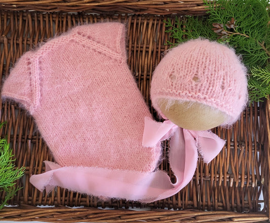 soft and fuzzy pink newborn baby girl romper with a bonnet with ribbon ties