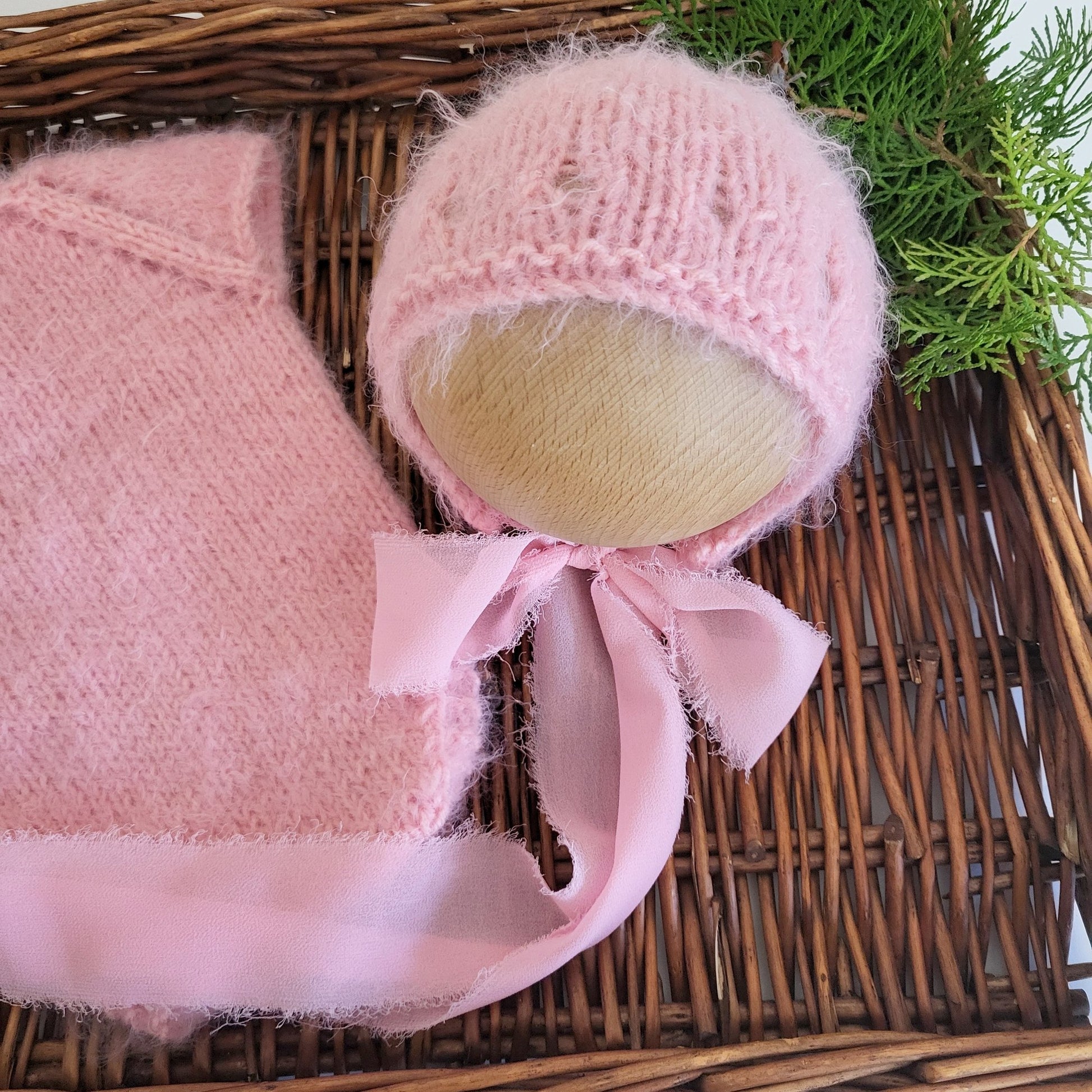 soft and fuzzy pink newborn baby girl romper with a bonnet with ribbon ties