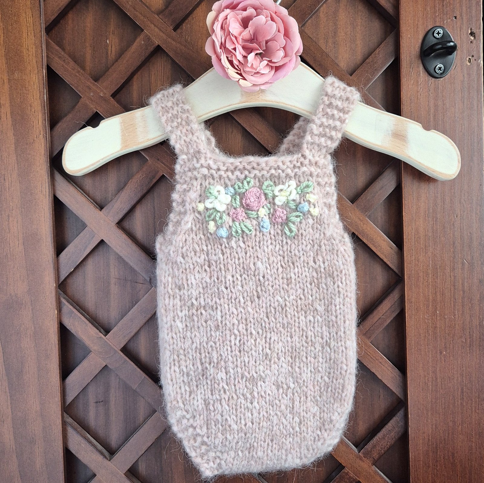 RTS Ready to send soft dusty pink newborn romper. A sleeveless baby girl romper for your babys first newborn photos. The little romper has embroidered flowers on the front of the bodice.
Handmade in soft alpaca yarn that is soft and stretchy,
and will fit a baby of approx 0-1 month old.

The shoulder straps are knit, and have a wooden button at the back.

This is a lovely addition to your newborn photography prop stash, and can be used in almost any layout, with any backdrop, and is ideal for summertime, fo