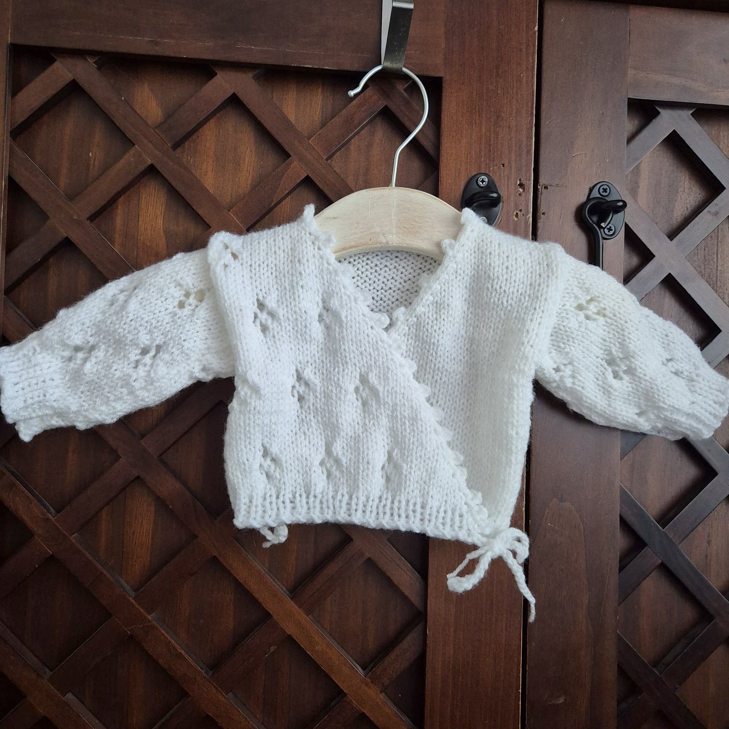 Hand knit baby girl cardigan outfit. Newborn cross over kimono style cardigan with a lace Pattern, scalloped edge, and long sleeves. The fronts have bow-ties at the edge.

Made in sizes Preemie / Newborn / 0-3 months
A pair of matching pants with the same pattern completes the outfit. Knit in soft acrylic yarn that is easy to wash.
This is perfect as a hospital coming home outfit, newborn photography prop or as a baby shower gift for a baby girl. All my knitwear is shipped in an organza bag, ready for you t