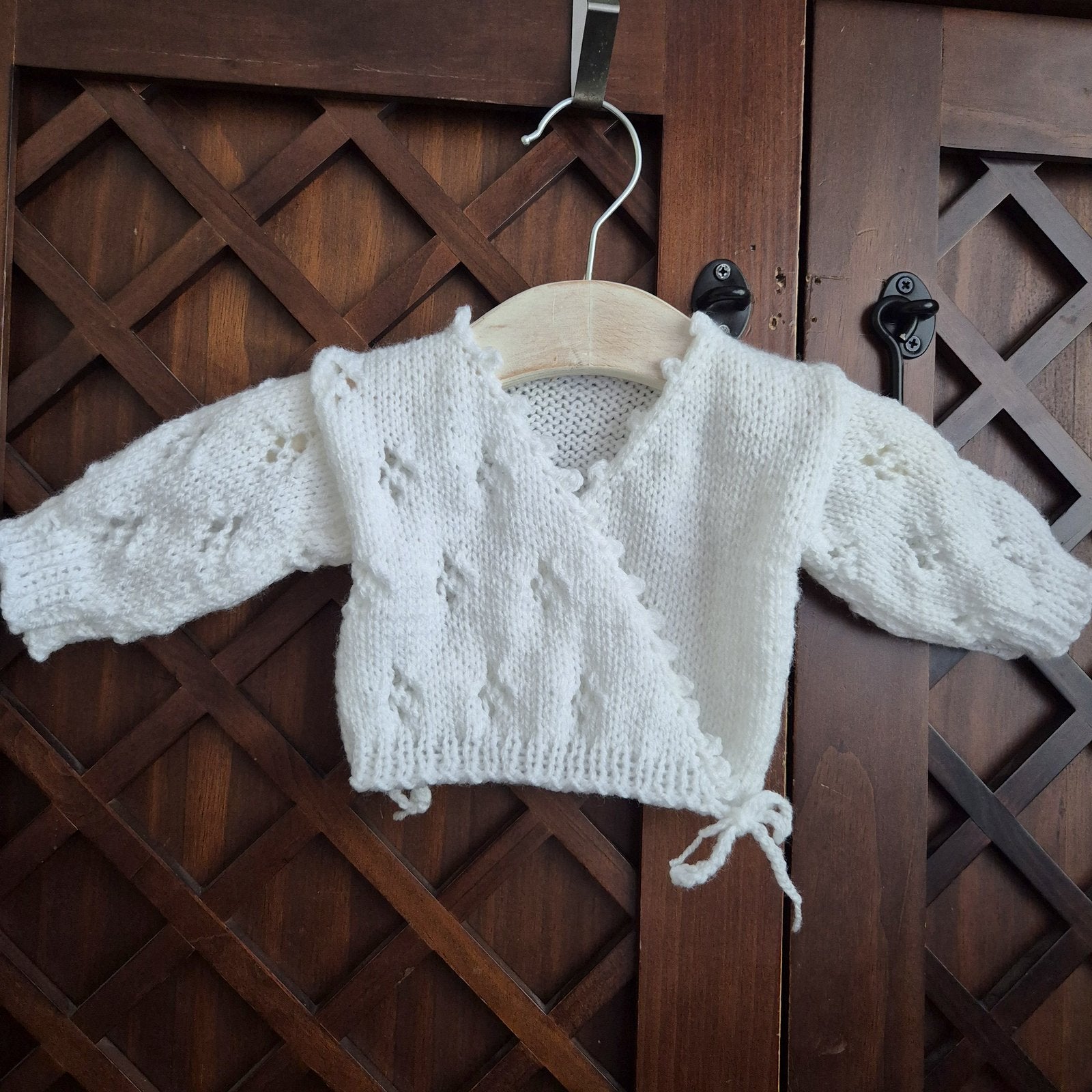 Hand knit baby girl cardigan outfit. Newborn cross over kimono style cardigan with a lace Pattern, scalloped edge, and long sleeves. The fronts have bow-ties at the edge.

Made in sizes Preemie / Newborn / 0-3 months
A pair of matching pants with the same pattern completes the outfit. Knit in soft acrylic yarn that is easy to wash.
This is perfect as a hospital coming home outfit, newborn photography prop or as a baby shower gift for a baby girl. All my knitwear is shipped in an organza bag, ready for you t
