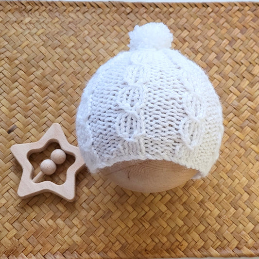white knitted pom pom beanie for a new baby