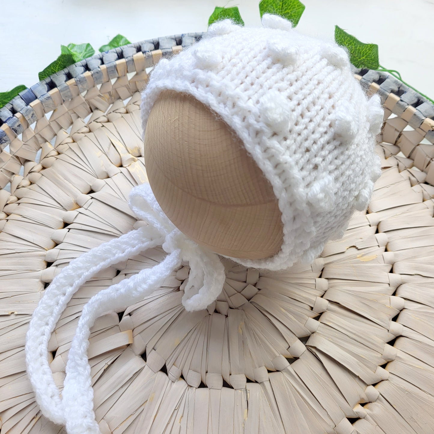 handknit white baby bonnet with bubble pattern and crochet neck ties ideal as a baby shower gift