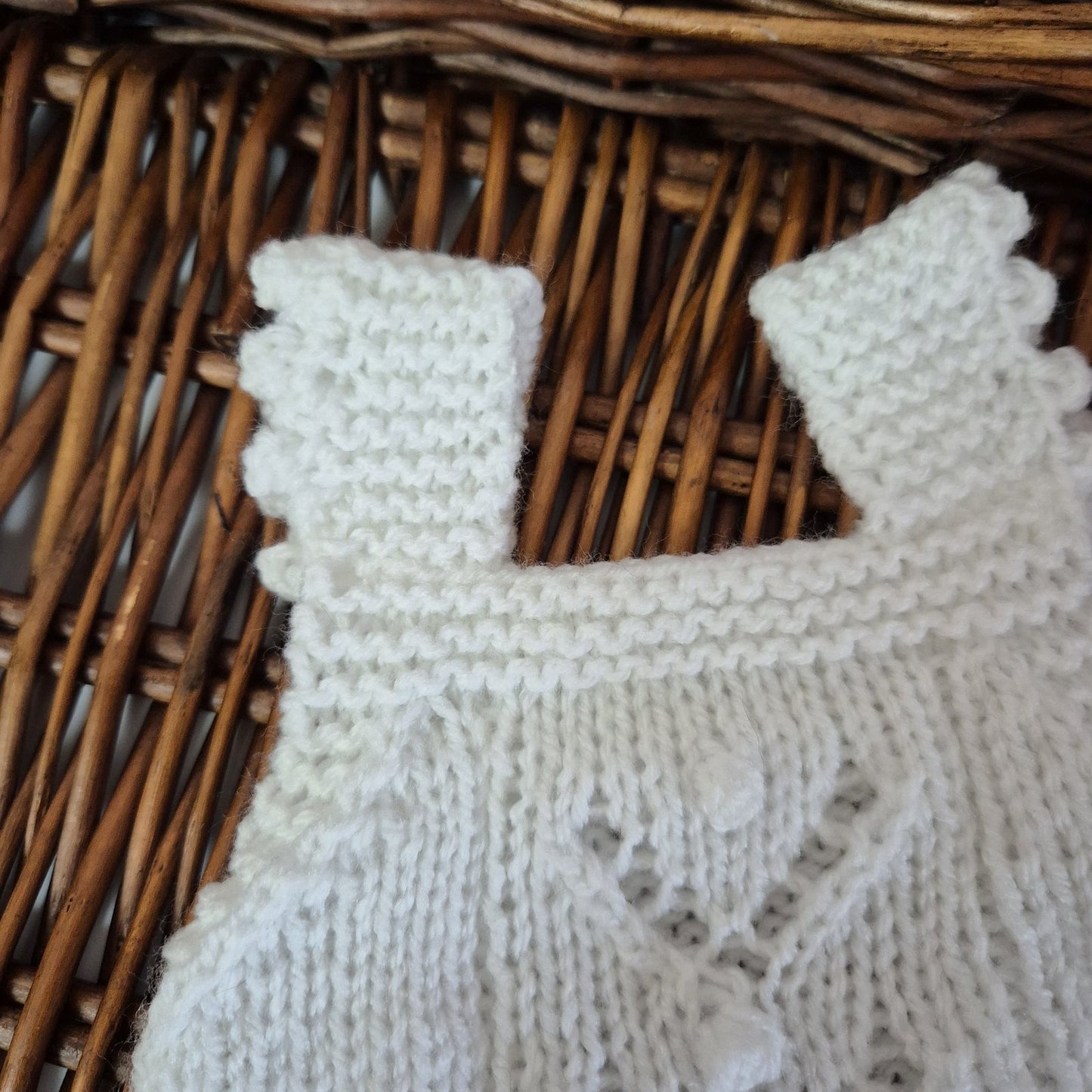 Close-up of a white knitted fabric with lace pattern on a wicker surface