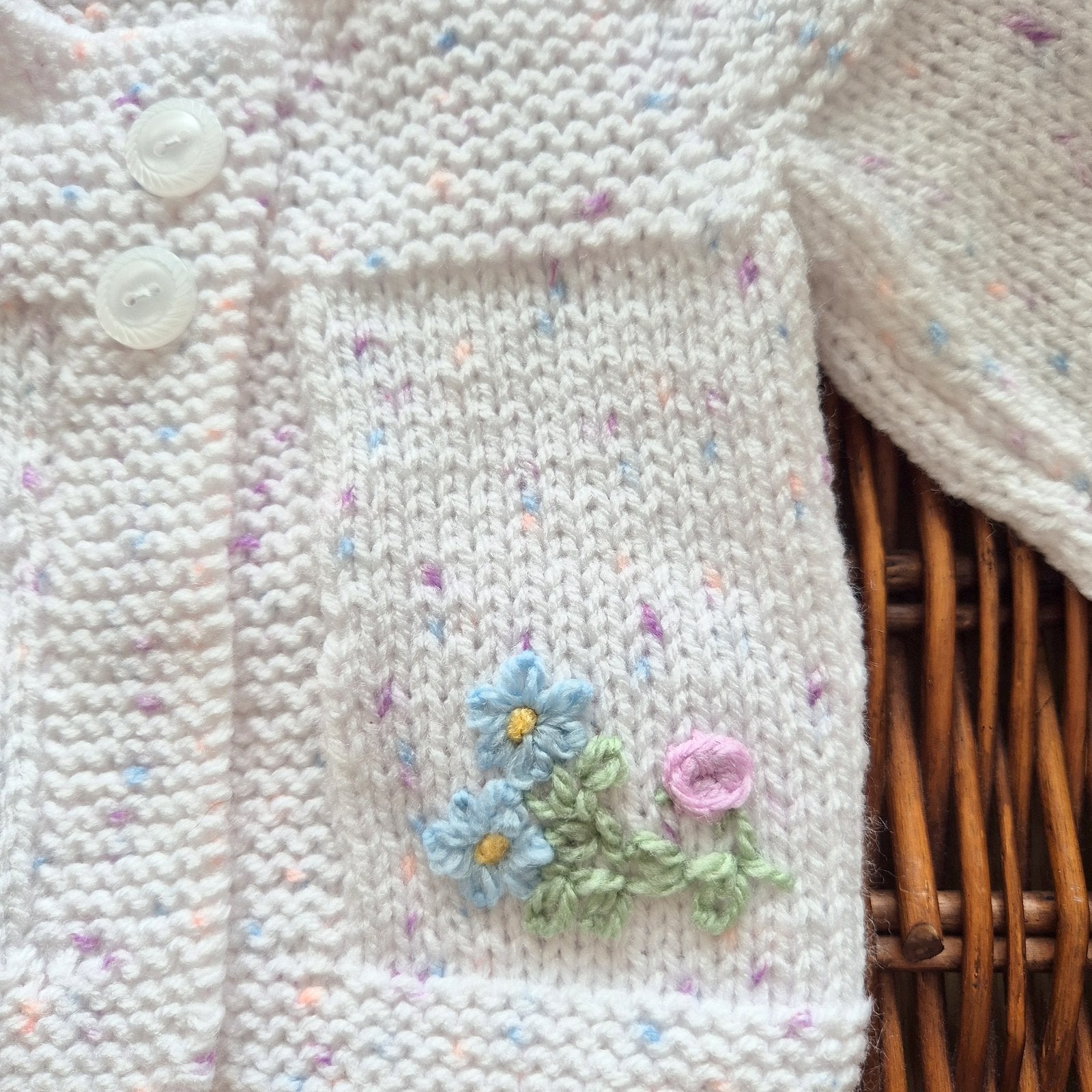 Knitted cardigan with floral embroidery and buttons on a wooden surface