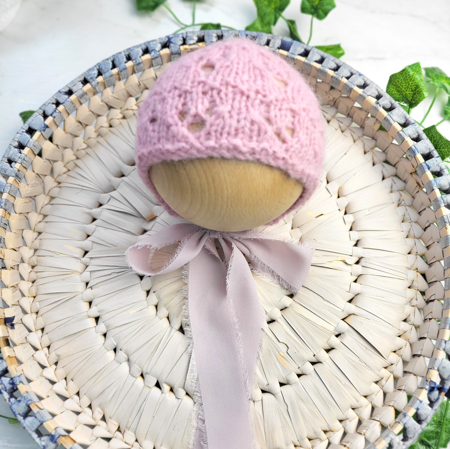 handknit newborn baby girl bonnet in pink with lacy pattern and ribbon neck ties